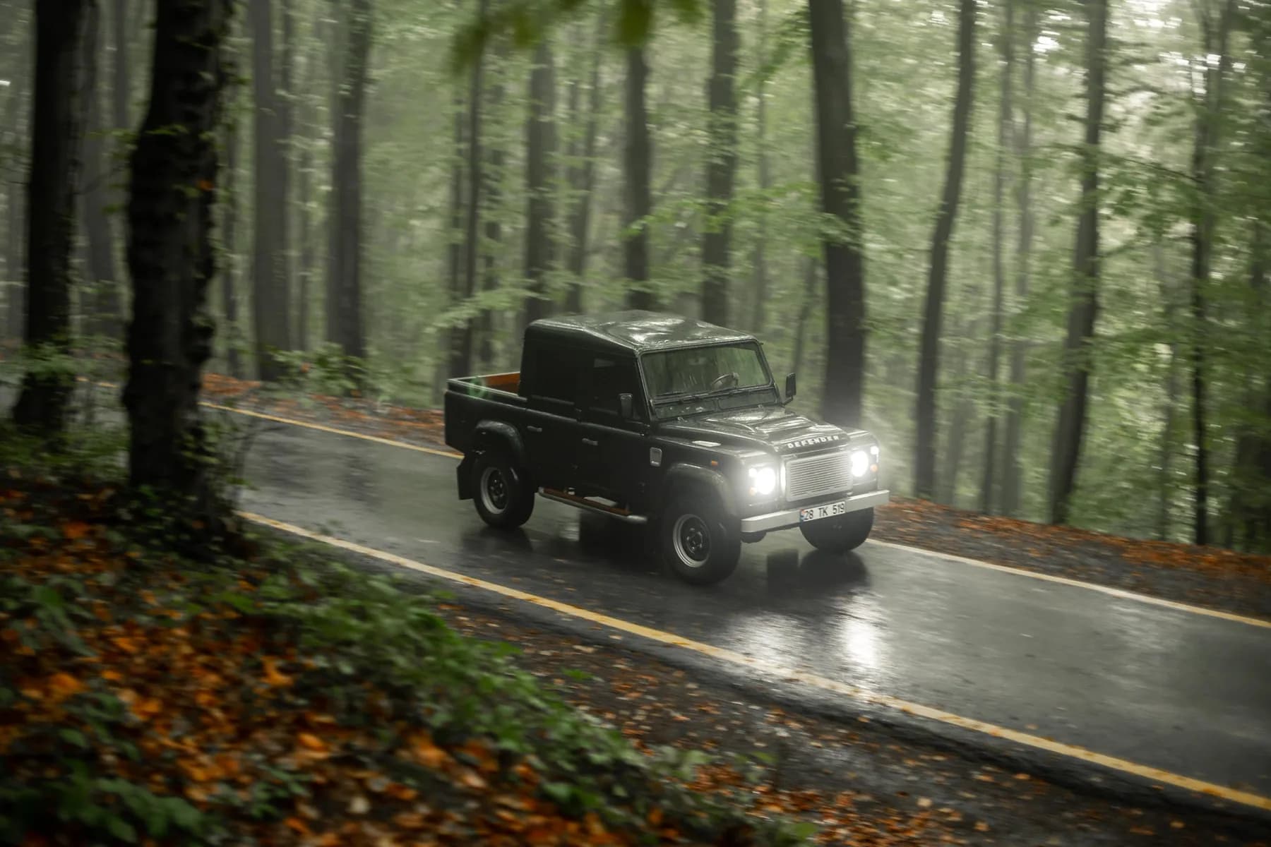 Dark green Altera Defender 110 Crew Cab on a wet forest road