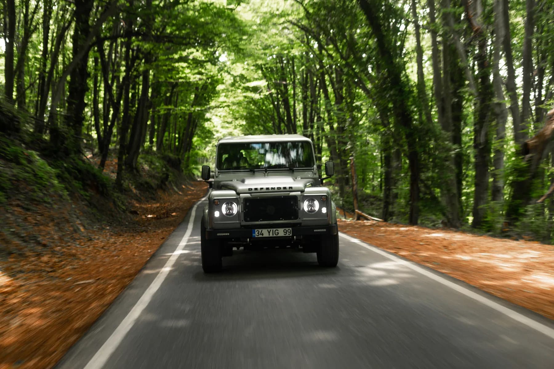 Grey Altera Defender 110 driving through a forest