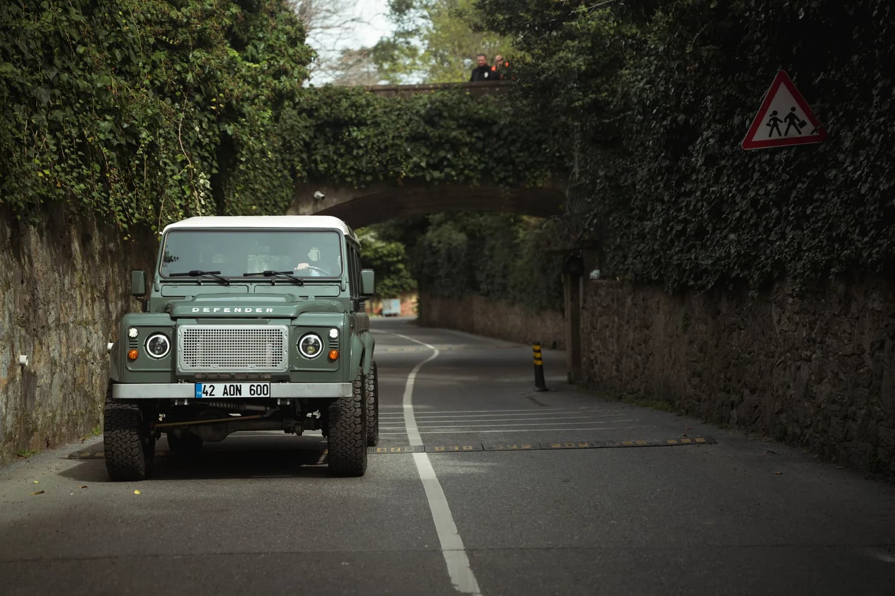 Heritage green Altera Defender 110 approaching on a wooded road